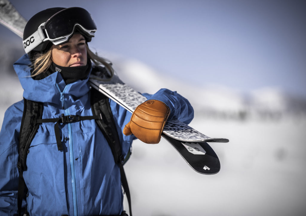 Skier wearing Hestra Fall Line Cork/Cork gloves carrying skis. Photo: HESTRA