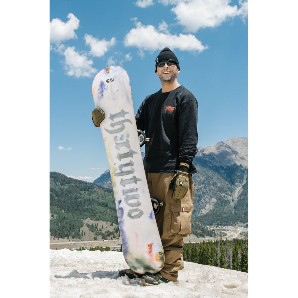 Scott Stevens holding his Middle Earth Pro snowboard in the mountains