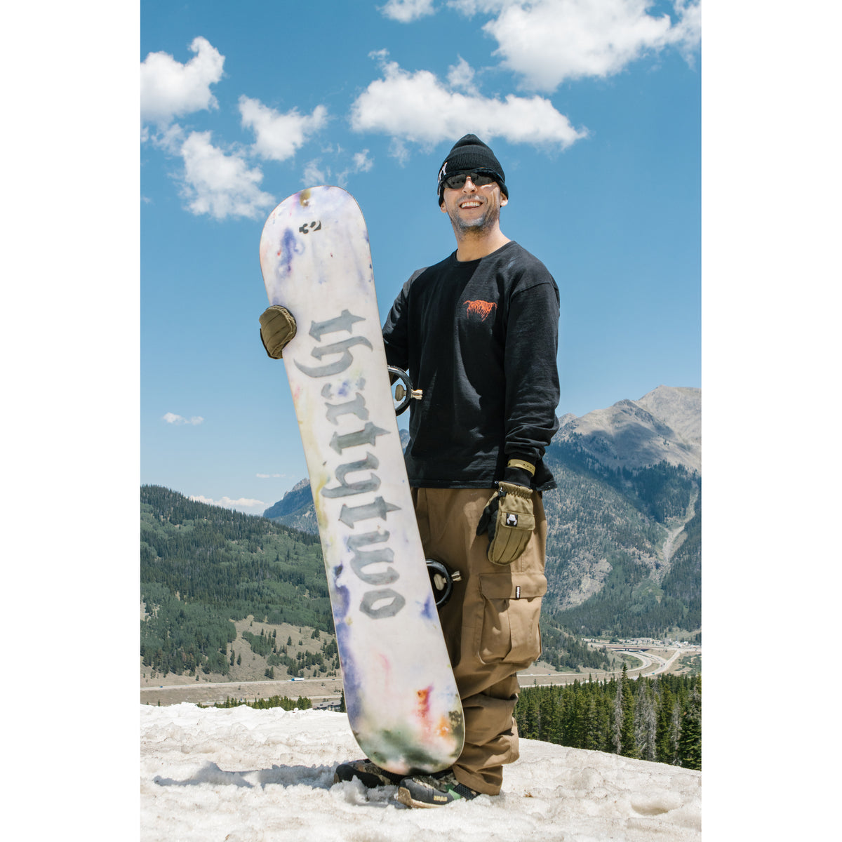 Scott Stevens holding his Middle Earth Pro snowboard in the mountains