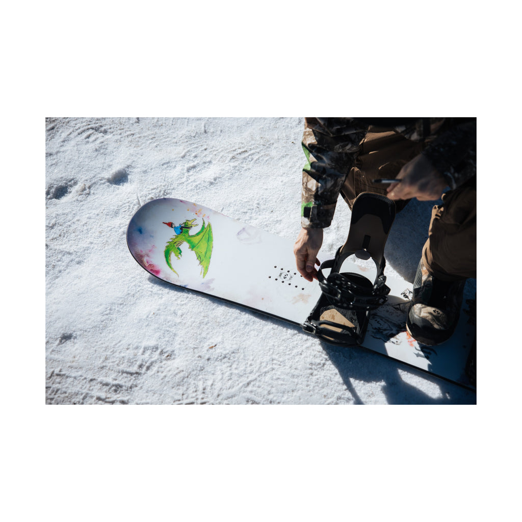 Middle Earth Pro snowboard topsheet nose graphic and binding detail on snow