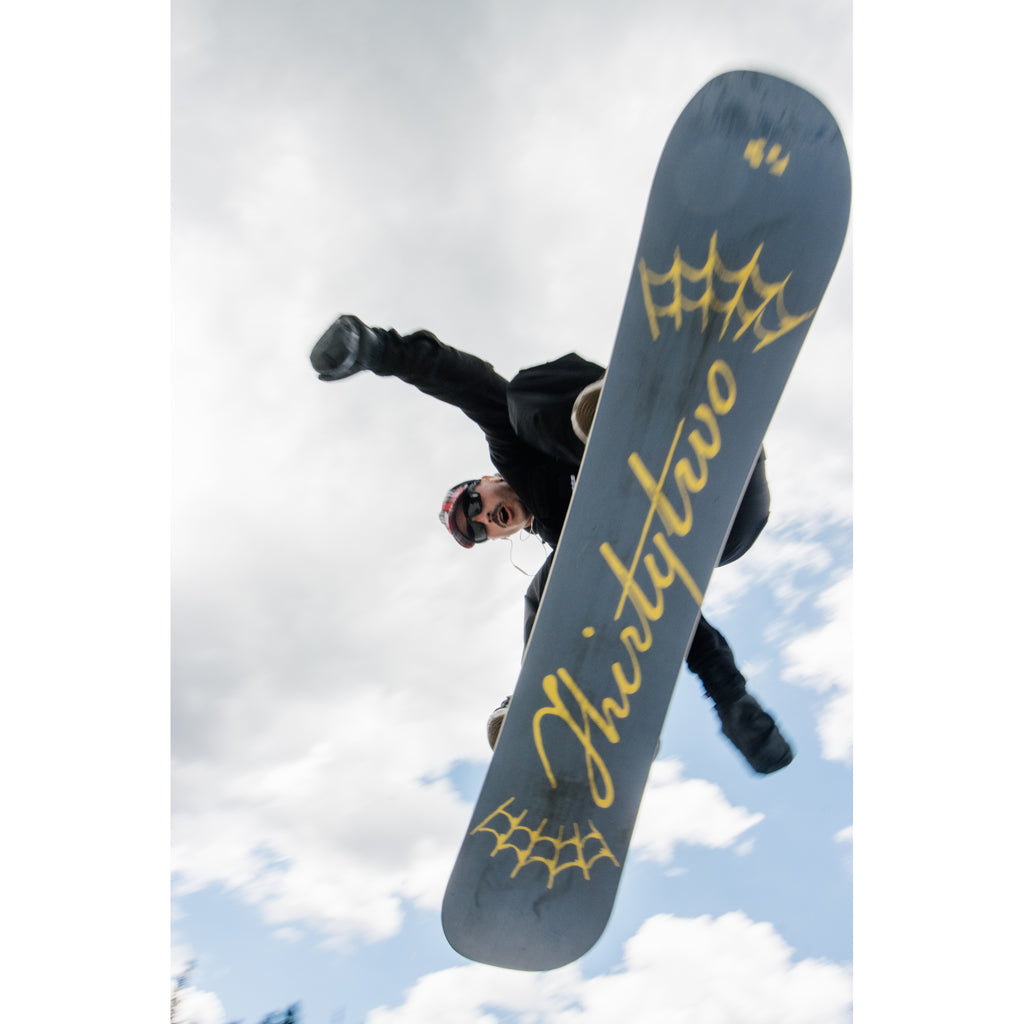 Rider jumping with the Permanent Vacation snowboard base visible