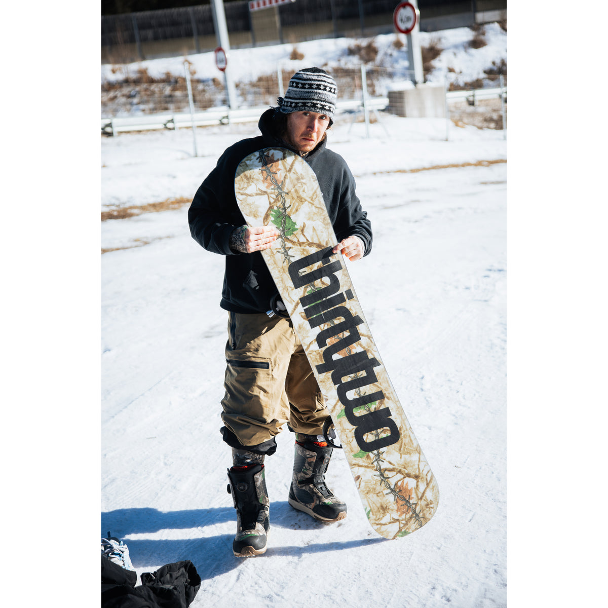 Rider holding the camouflage T32M snowboard in the snow