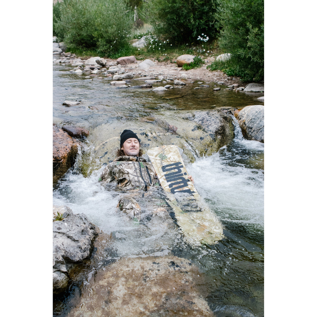 Rider with the camouflage T32M snowboard in a mountain creek