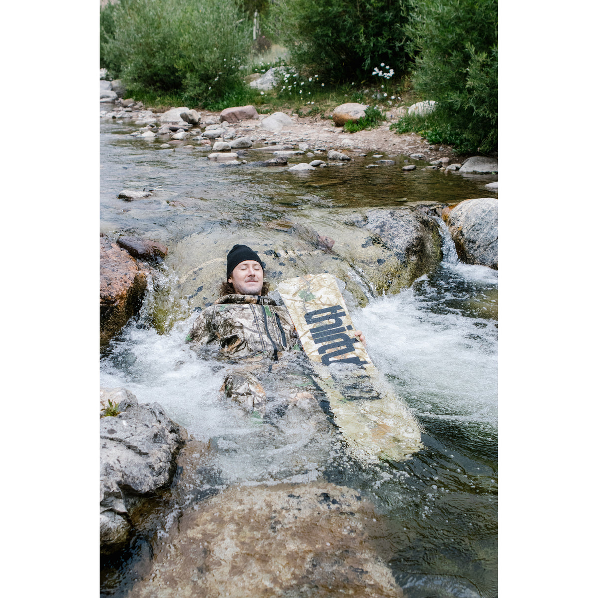 Rider with the camouflage T32M snowboard in a mountain creek